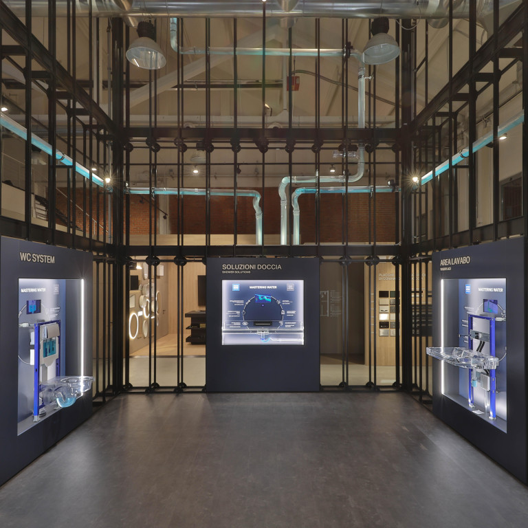 A modern exhibition space with glass and metal structures showcasing high-tech displays and informational panels.