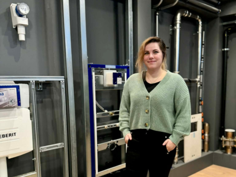 A person stands in a modern interior featuring plumbing equipment.