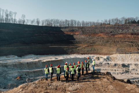 A group of people wearing safety vests stands at the edge of Trench.
