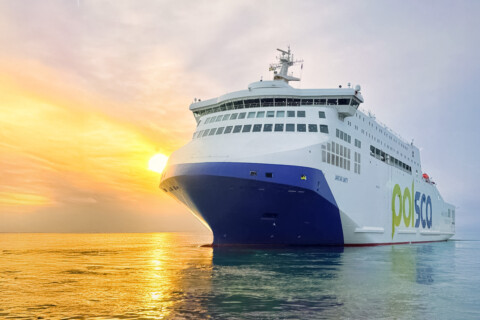A large ferry sailing on calm waters during sunset.