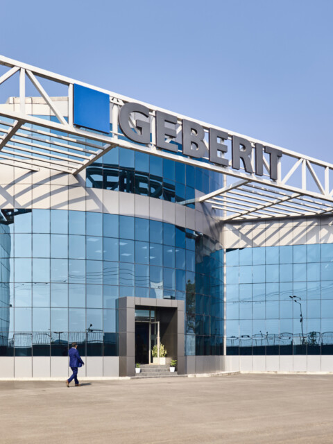 Modern corporate building with large glass windows and a blue and grey facade, featuring the name "Geberit" prominently displayed.