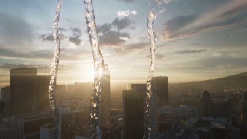 Wasserstrahlen im Vordergrund, vor einer Stadtsilhouette bei Sonnenuntergang.