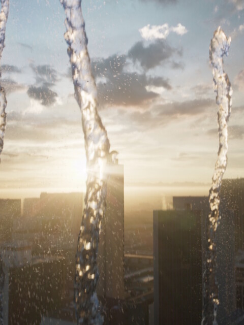 Wasserstrahlen im Vordergrund, vor einer Stadtsilhouette bei Sonnenuntergang.