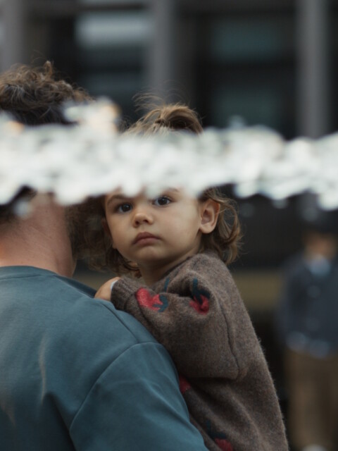 A person holding a child with water splashing in the foreground.