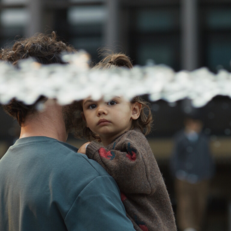 A person holding a child with water splashing in the foreground.