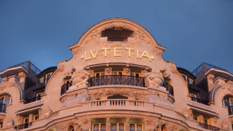 Fassade eines historischen Gebäudes mit dem Schriftzug "Lutetia" und Verzierungen, beleuchtet bei Dämmerung.