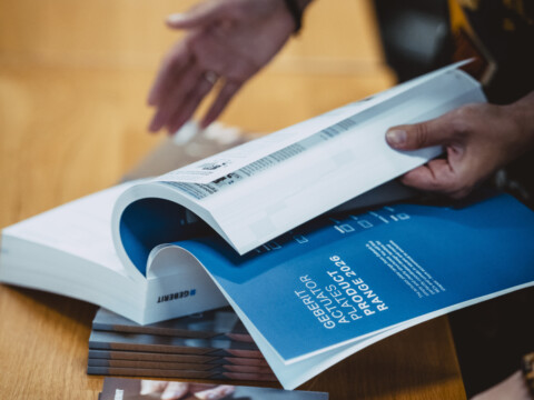 Eine Person blättert durch ein aufgeschlagenes Buch auf einem Tisch.