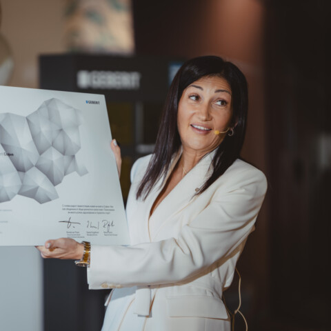 Eine Frau in einem stylischen weissen Anzug hält eine Grafik mit einer Karte in der Hand und lächelt.