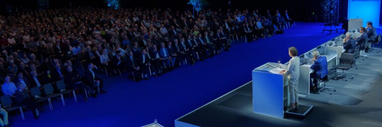 Fully occupied conference hall with lectern and audience looking towards the stage