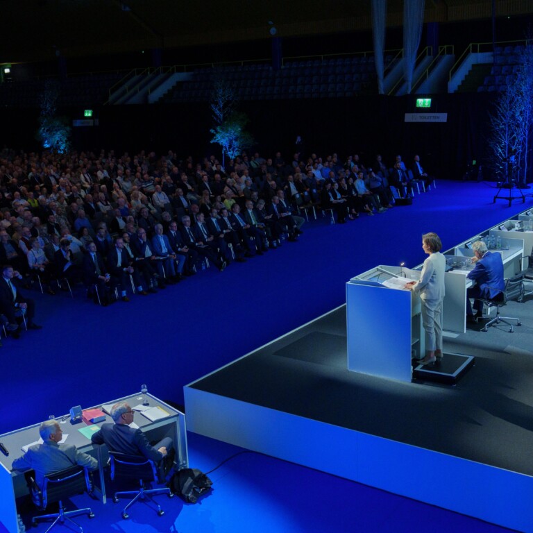 Fully occupied conference hall with lectern and audience looking towards the stage