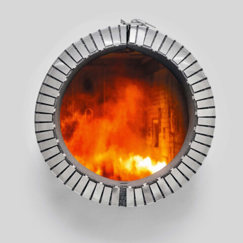 Eine runde Feuerkammer mit einem Rand aus weissen Ziegeln, die orangefarbene Flammen zeigt, die darin brennen.