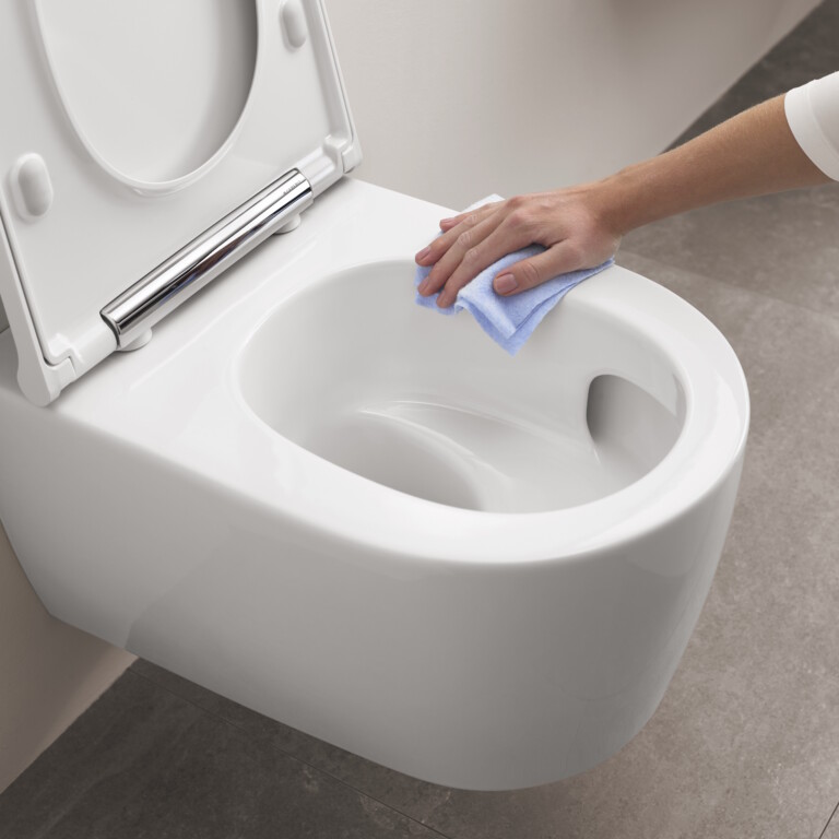 Eine Hand wischt mit einem blauen Tuch eine saubere, weisse, Toilette ab