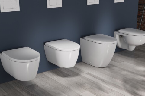 Eine Reihe weisser Toiletten unterschiedlicher Bauart vor einer dunkelblauen Wand in einem Badezimmer.