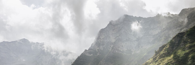 Sunlight breaking through clouds to illuminate a vast, green, forested mountain range.