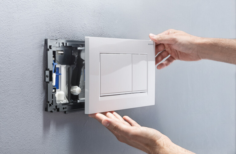 A white actuator plate that is carefully attached to a bracket in the wall.